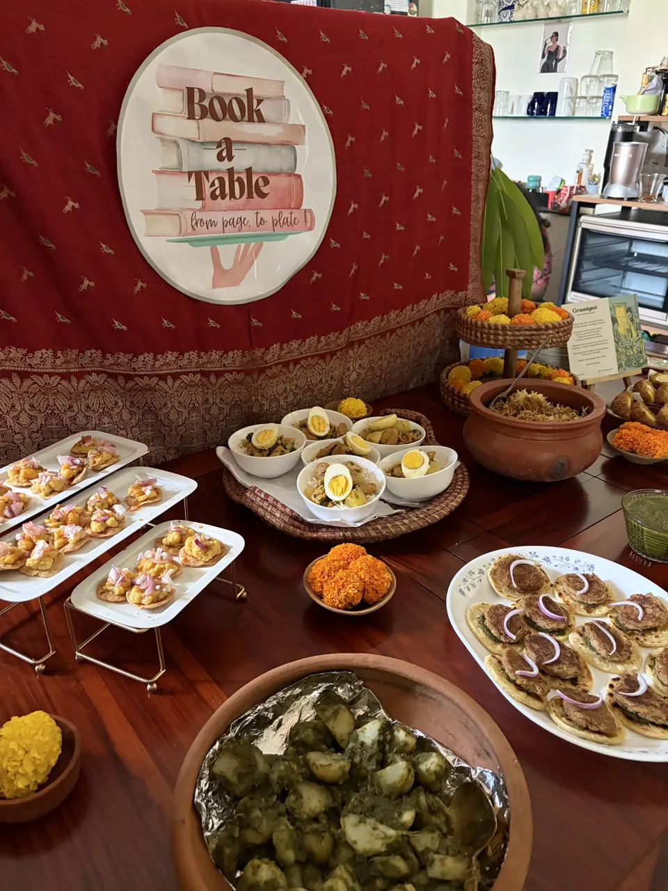 Buffet of chaat-topped puris, egg curry bowls, clay-pot rice and kebabs beneath the Book a Table sign