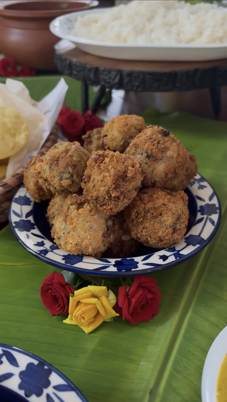 Crumb-fried golden croquettes piled in a blue-and-white bowl with red and yellow roses