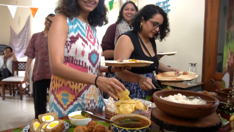 Smiling guests serve themselves papad, rice and egg chops from the banana-leaf buffet