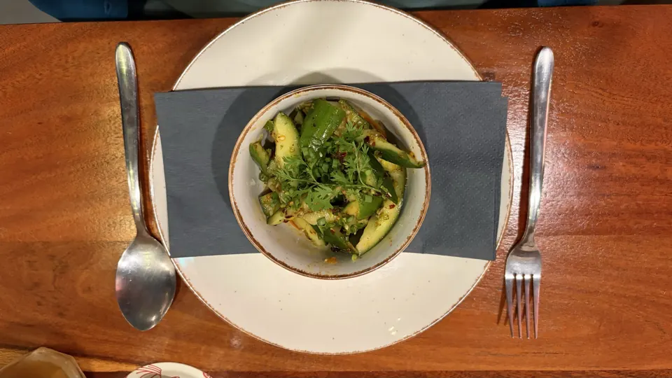 Overhead view of a cucumber salad with chilli flakes and fresh coriander in a rustic bowl