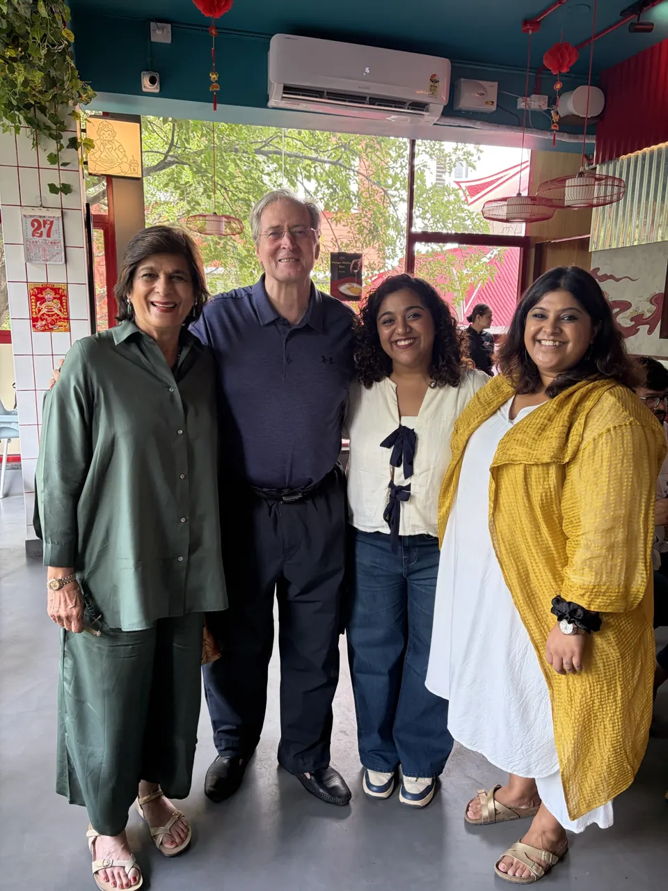 Four people smiling together in the Bao To Me dining room, lanterns and greenery behind